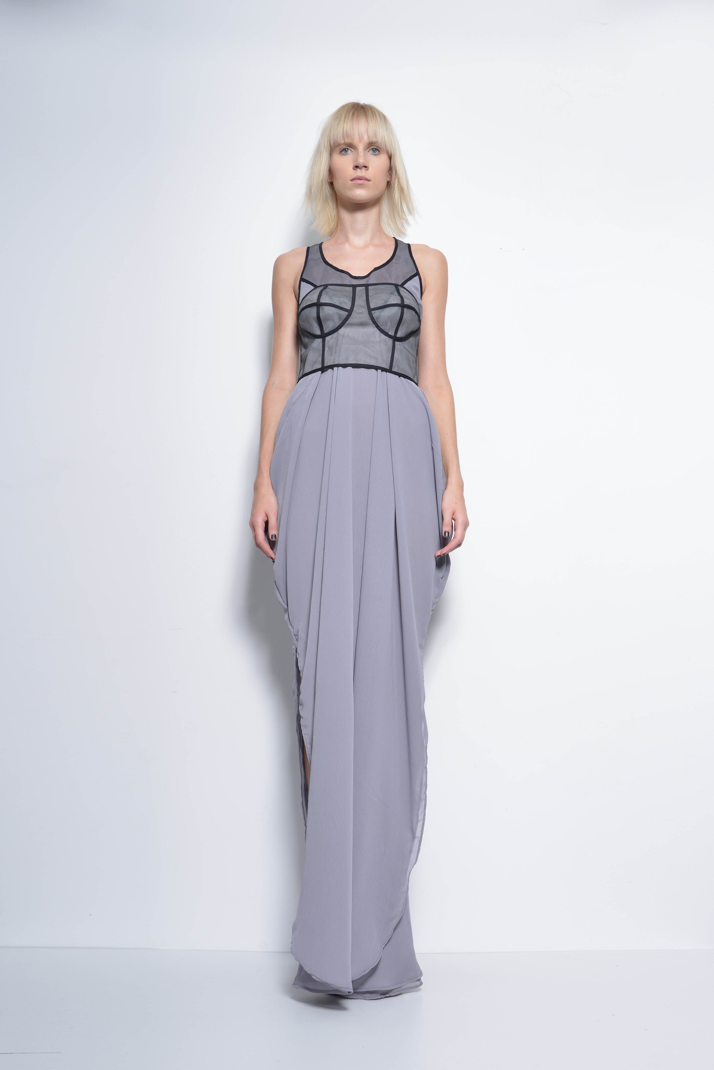 Woman wearing a long gray dress with a black mesh top on a white background