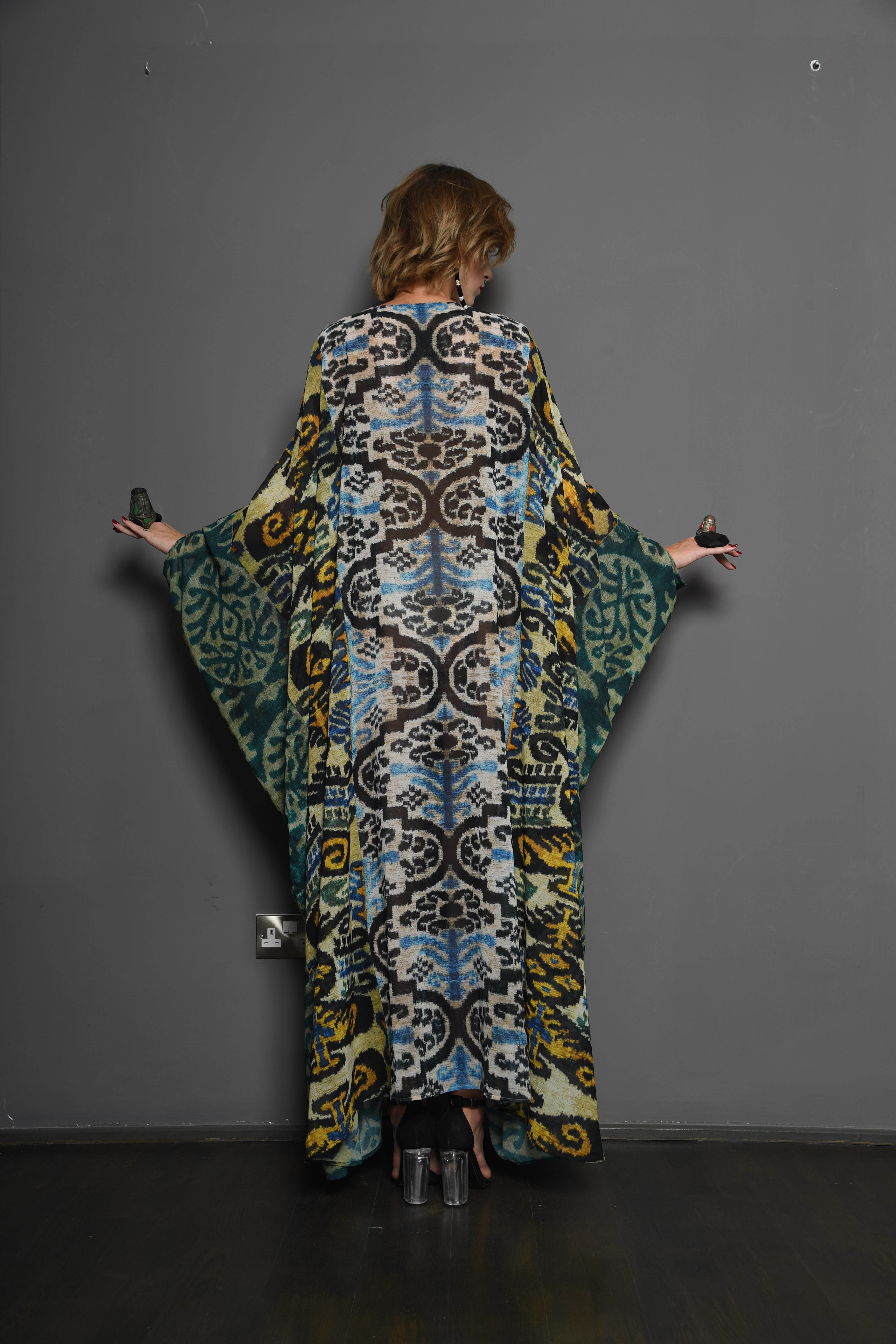 Person wearing a long, patterned dress against a plain background